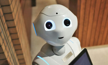 Robot androide che guarda verso la camera con espressione sorridente, introduzione all'Intelligenza Artificiale.